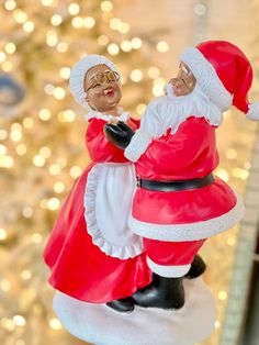 a santa clause figurine sitting on top of a white table next to a christmas tree