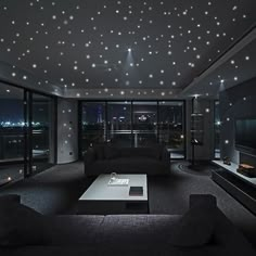 a living room filled with black furniture and stars on the ceiling above it's windows