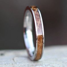 a wedding ring with wood inlays on the outside and inside, sitting on a stone surface