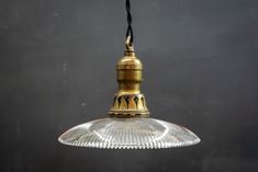 an old fashioned glass light hanging from a ceiling fixture with a black wall in the background