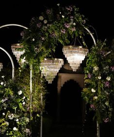 an archway with chandeliers hanging from it's sides and greenery on either side