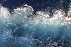 an aerial view of the ocean with waves and foamy blue water, taken from above