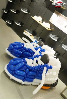 an inflatable pair of shoes is on display at a shoe store, with blue and white balloons attached to them