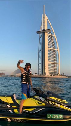 a man standing on top of a yellow and black jet ski