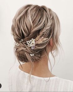 a woman with her hair in a low bun and some flowers on top of her head