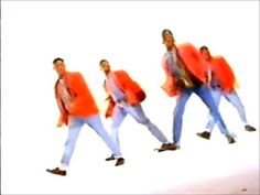 three men in orange jackets and blue jeans are dancing