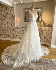 a white wedding dress on display in a room with floral wallpaper and rugs