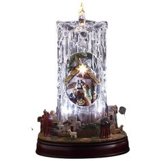 a lighted christmas clock with nativity scene in the center on a wooden base, surrounded by figurines