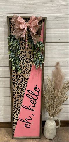 a pink and leopard print door hanger next to a potted plant