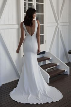 a woman in a white wedding dress is standing on the porch with her back to the camera