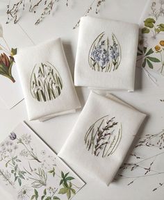 four embroidered napkins with flowers on them sitting on top of a table next to each other