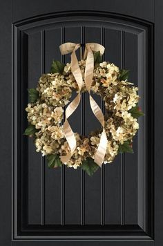 a black door with a wreath on the front and side panels that have gold ribbons hanging from it