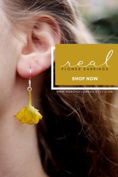 a close up of a person's ear with the words real flower earrings shop now