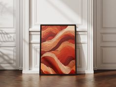 an abstract painting is displayed on the floor in front of a white paneled wall