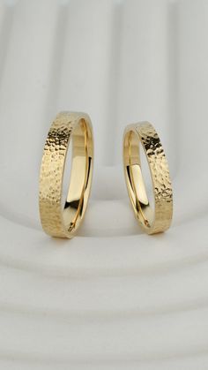 two gold wedding rings sitting on top of each other