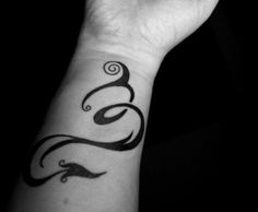 a woman's arm with a black and white tattoo design on the left wrist