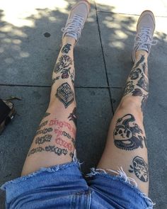 a person with tattoos sitting on the sidewalk