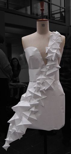 a dress made out of white paper sitting on top of a mannequin