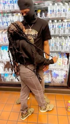 a man with dreadlocks is standing in front of a store display filled with bottled water