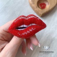 a woman's hand holding a red beaded lip ring