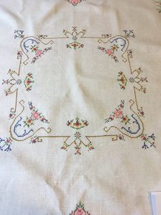 an embroidered tablecloth with flowers and birds on it