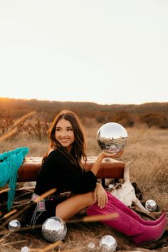 a woman sitting on the ground with a disco ball in her hand and other decorations around her