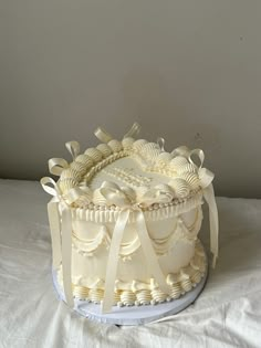 a large white cake sitting on top of a table covered in icing and ribbon