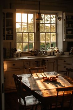 the kitchen table is in front of two windows with sunlight streaming through them and there are wooden chairs around it