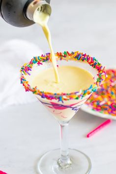 a martini being poured into a glass with sprinkles on the rim and saucer