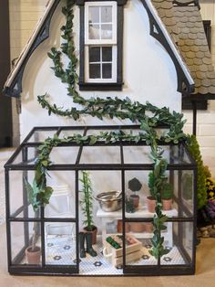 a miniature house made out of glass with plants growing on the roof and inside it