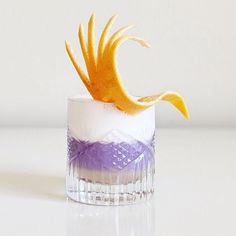 a small glass with an orange and purple decoration on it's rim, sitting on a white surface