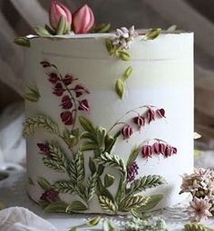 a close up of a cake with flowers on the frosting and leaves around it