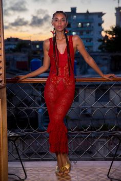 a woman in a red dress standing on a balcony