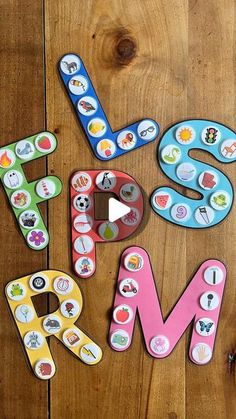 the letters are made up of different types of magnets and stickers on a wooden surface