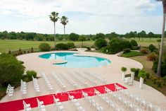 an aerial view of a pool and lawn with chairs set up for a wedding ceremony