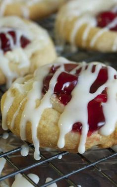 cookies with white icing and raspberry toppings sitting on a cooling rack