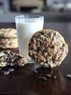 chocolate chip cookies and milk are sitting on a table next to the cookie, which has been cut in half