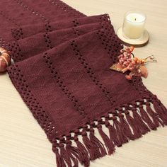 a knitted table runner with tassels and a candle