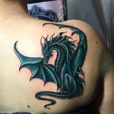 the back of a man's shoulder with a blue dragon tattoo on his chest