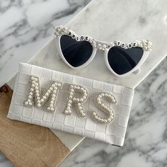 the bride sunglasses and purse are sitting on top of a marble slab with pearls attached to it