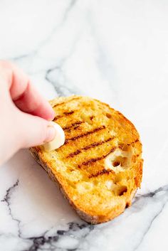 someone is dipping cheese on top of a grilled piece of bread that has been cut in half