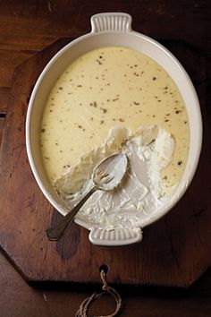 a white bowl filled with soup on top of a wooden table next to a spoon