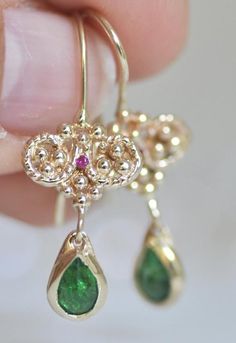 14k gold earring, small red Ruby and hanging green Emerald stones.  These yellow gold earrings have two parts: Dainty gold balls with a small red Ruby stone between the balls. Hanging teardrop beautiful Emerald on a solid gold bezel. #ruby #emerald #goldearrings #malkaravinajewelry Elegant Green 14k Gold Earrings, 14k Gold Jewelry Set With Green Matching Earrings, Exquisite Green Teardrop Earrings, Pierced Yellow Gold Emerald Earrings, 14k Gold Green Pierced Earrings, Green 14k Gold Dangle Earrings, Green Briolette Earrings For Pierced Ears, 14k Gold Green Earrings With Ear Wire, Green Single Earring In 14k Gold