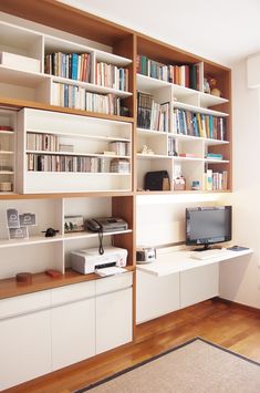 a living room filled with lots of bookshelves next to a desk and tv