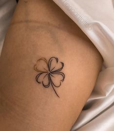 a small four leaf clover tattoo on the side of a woman's thigh,