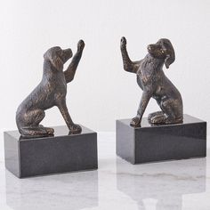 two bronze figurines of dogs standing on their hind legs, one holding the other's hand