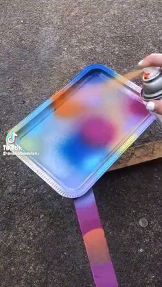 a person is holding a mouse in front of a plastic tray with colorful paint on it