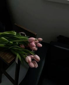 a bunch of pink tulips sitting on top of a wooden table next to a window