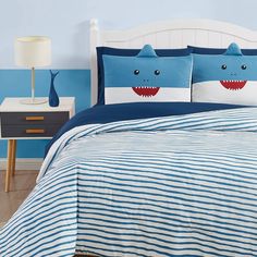 a bed with blue and white striped bedspread, two pillows and a shark pillow