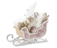 a small toy sleigh with feathers and balls in it on a white background